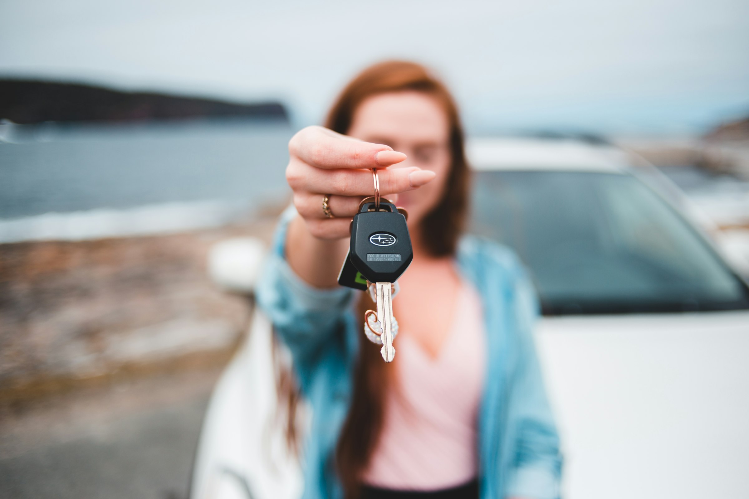 Car keys held in front of a new car